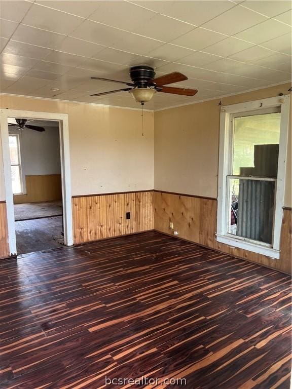 unfurnished room featuring a paneled ceiling, dark hardwood / wood-style floors, ceiling fan, and wood walls