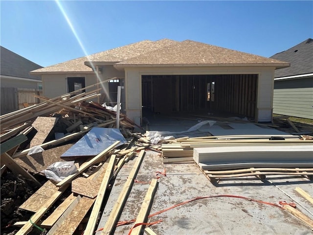 rear view of house featuring a garage and fence