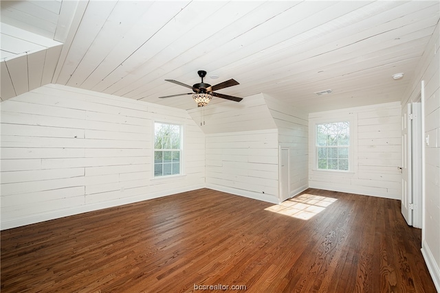 bonus room featuring plenty of natural light, wood walls, lofted ceiling, and dark wood-type flooring