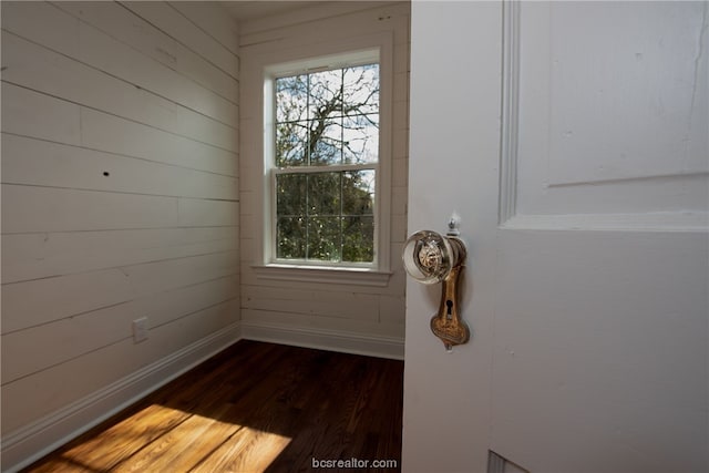 doorway featuring wood walls and dark hardwood / wood-style flooring