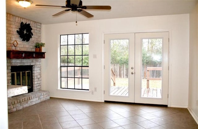 entryway featuring french doors, ceiling fan, tile patterned floors, and a brick fireplace