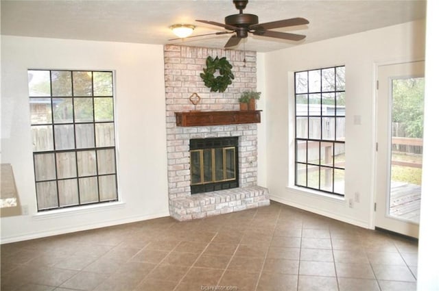 unfurnished living room featuring a brick fireplace, tile patterned floors, and ceiling fan