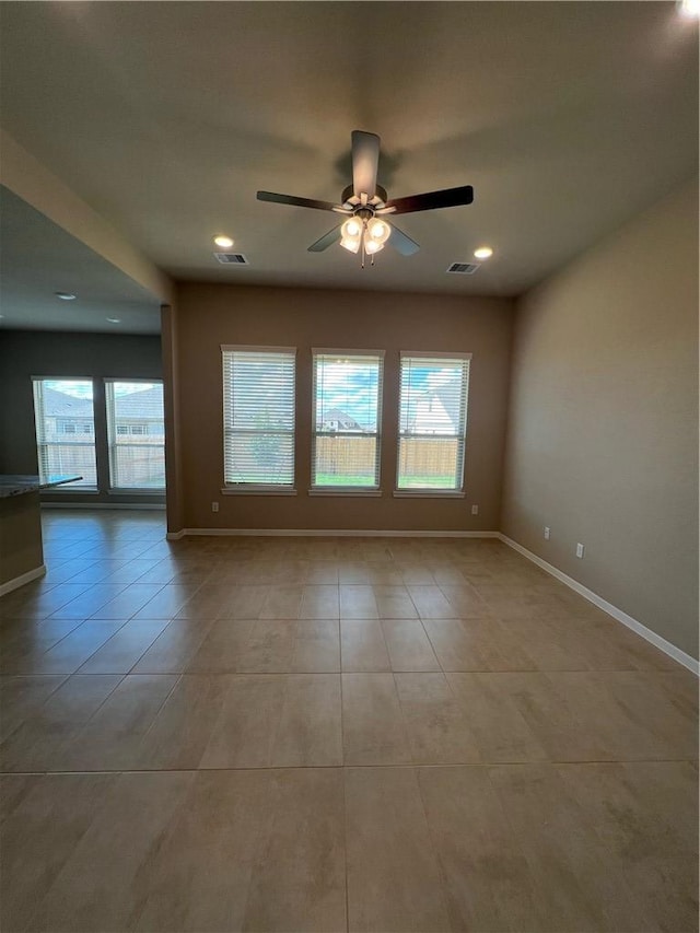 tiled spare room featuring plenty of natural light and ceiling fan