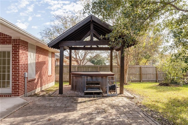 deck with a gazebo, a patio, a hot tub, and a lawn