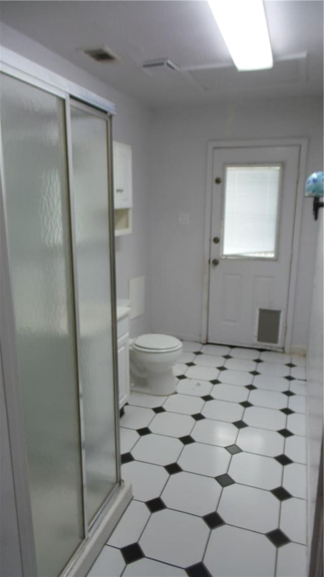 bathroom featuring vanity, a shower with shower door, and toilet