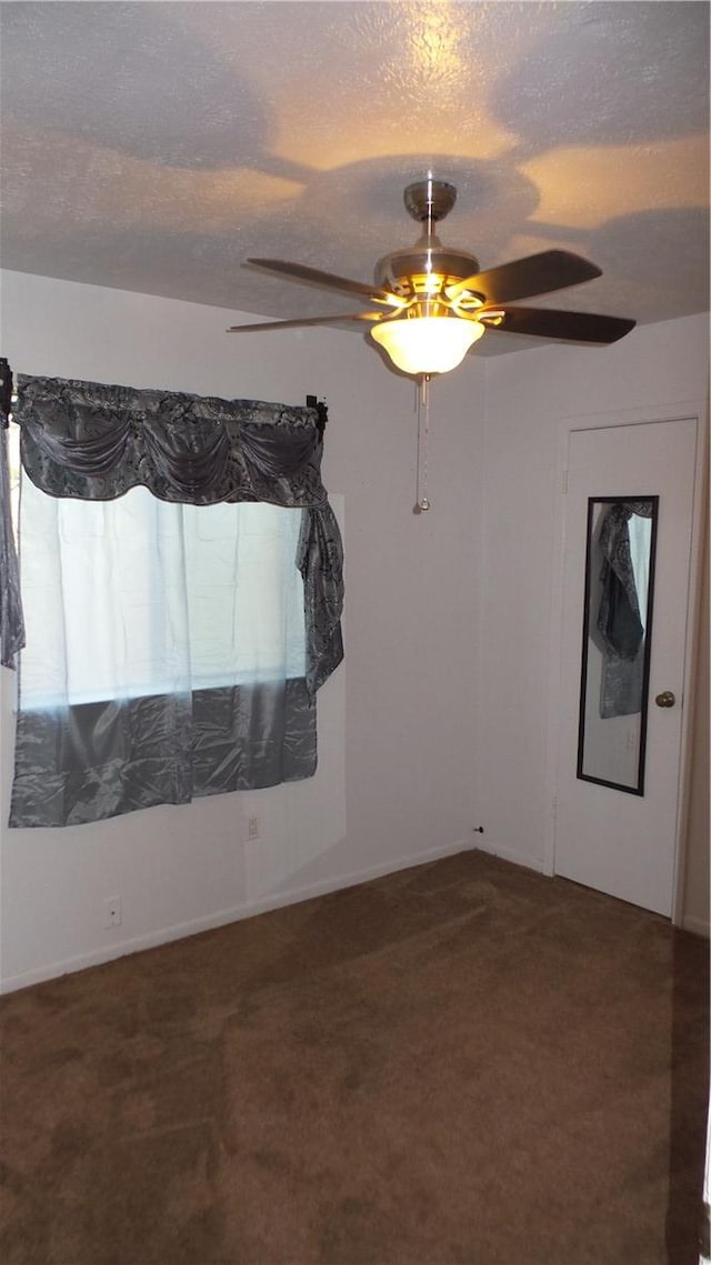 empty room with ceiling fan, carpet floors, and a textured ceiling