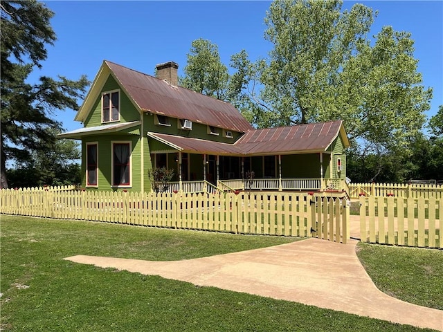 1100 Maple, Calvert, TX 77837 - view of front facade featuring a chimney, metal roof, a front yard, and a fenced front yard