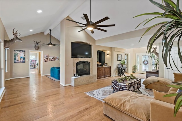 living room with a fireplace, beamed ceiling, plenty of natural light, and light wood-type flooring