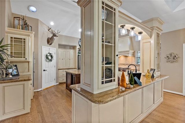 bar featuring decorative backsplash, light wood-type flooring, stone counters, and cream cabinets