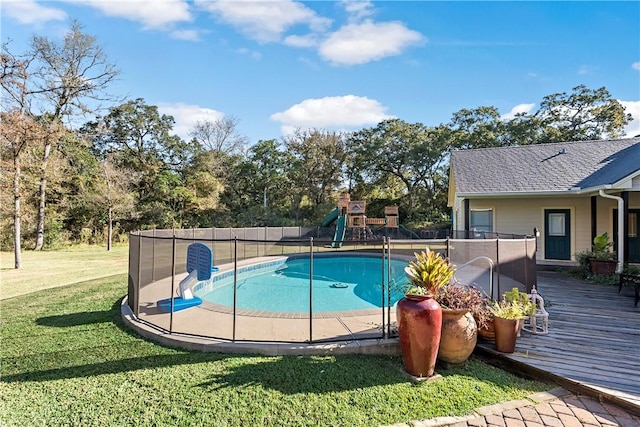 view of pool with a playground, a yard, and a wooden deck