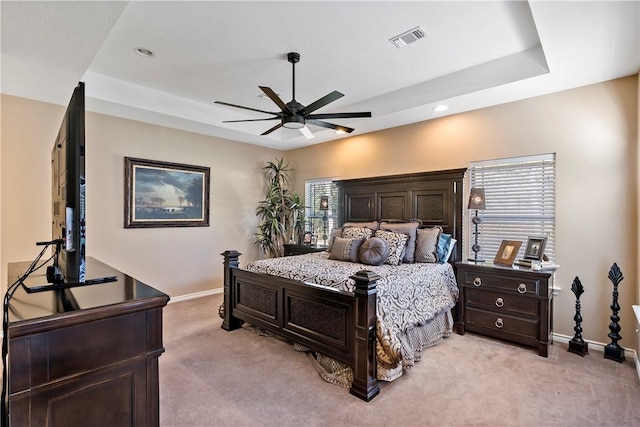 bedroom with a tray ceiling, light carpet, and ceiling fan