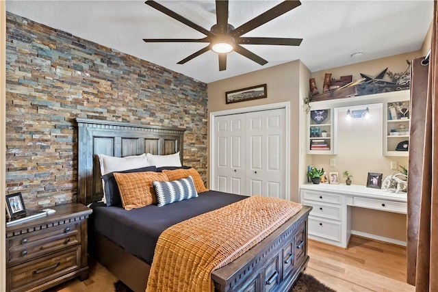 bedroom featuring a closet, light hardwood / wood-style floors, ceiling fan, and built in desk