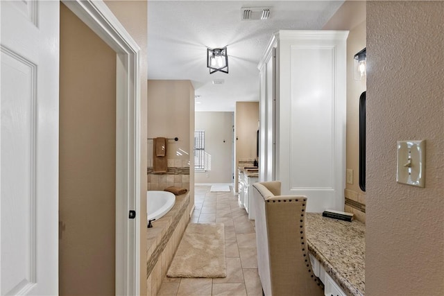 bathroom featuring vanity, tile patterned floors, and tiled tub