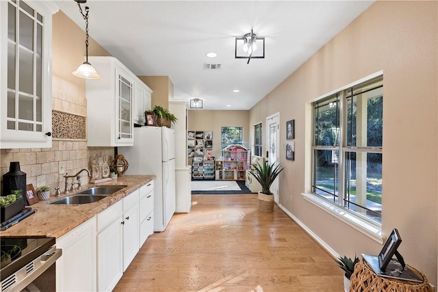 kitchen with light stone countertops, sink, a healthy amount of sunlight, and decorative light fixtures