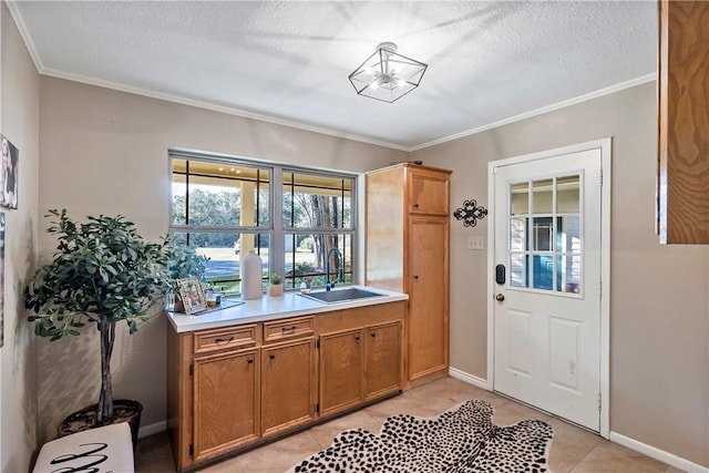 interior space with light tile patterned floors, a textured ceiling, ornamental molding, and sink