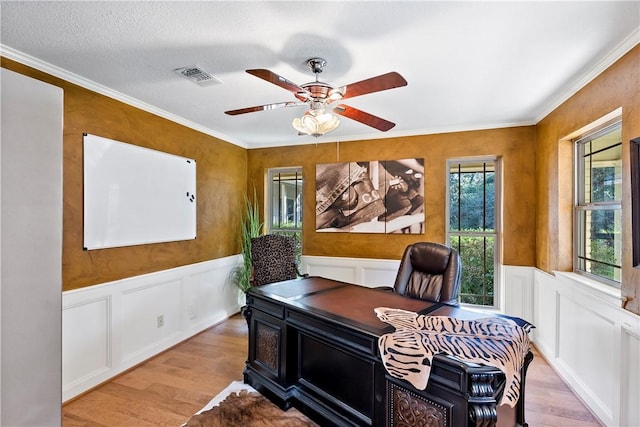 office featuring a textured ceiling, light wood-type flooring, ceiling fan, and ornamental molding