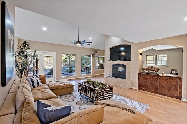 living room with lofted ceiling, a fireplace, a wealth of natural light, and light hardwood / wood-style flooring