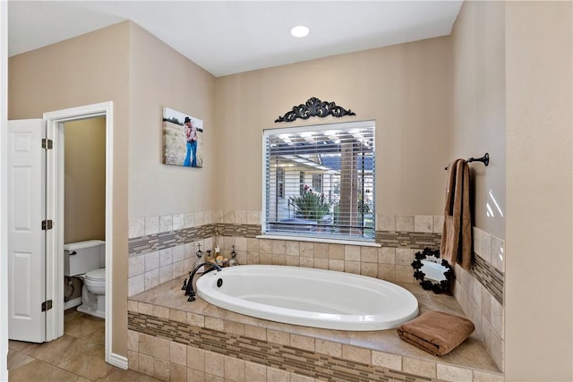 bathroom with tiled tub, tile patterned flooring, and toilet