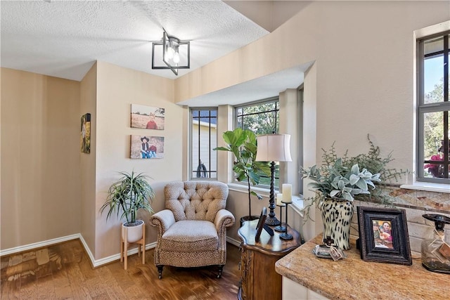 living area with a wealth of natural light, hardwood / wood-style floors, and a textured ceiling