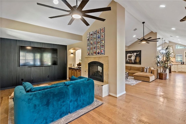 living room with hardwood / wood-style floors, beamed ceiling, high vaulted ceiling, and a tiled fireplace