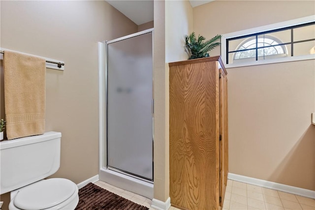 bathroom featuring a shower with door and toilet