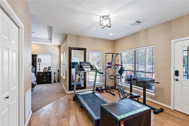 workout area featuring a textured ceiling and light hardwood / wood-style flooring