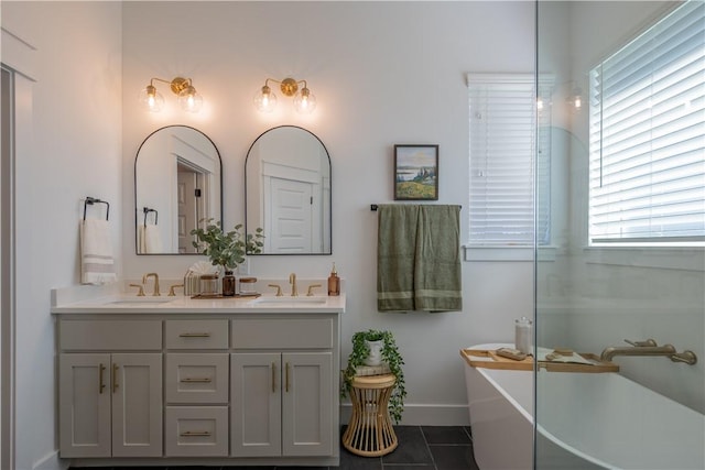 bathroom featuring tile patterned flooring, double vanity, a soaking tub, and a sink