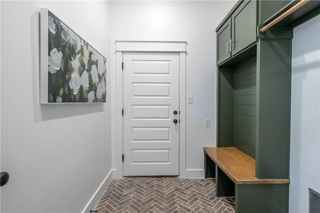 mudroom featuring brick floor and baseboards