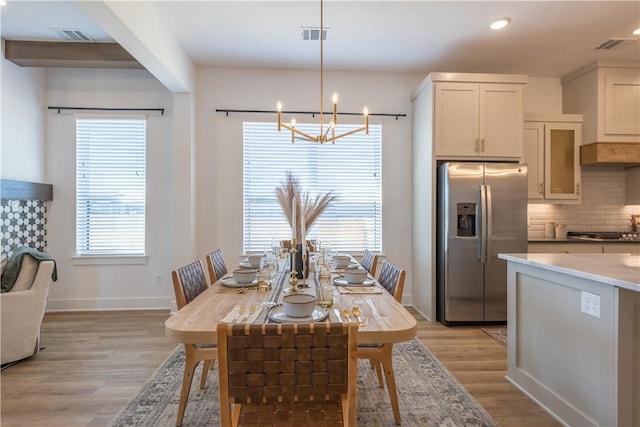 dining space with a healthy amount of sunlight, visible vents, light wood finished floors, and baseboards