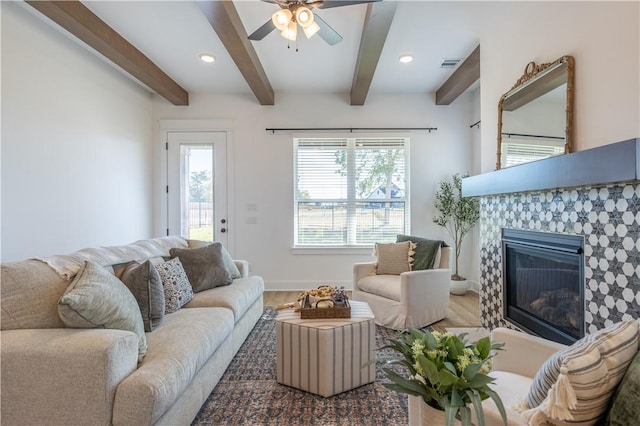 living room featuring beamed ceiling, wood finished floors, visible vents, and a tile fireplace