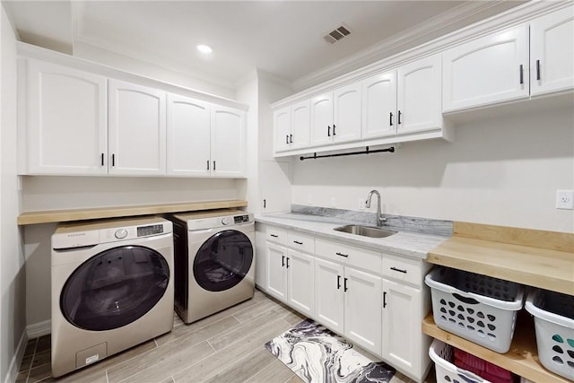 laundry room with cabinets, washing machine and dryer, crown molding, and sink