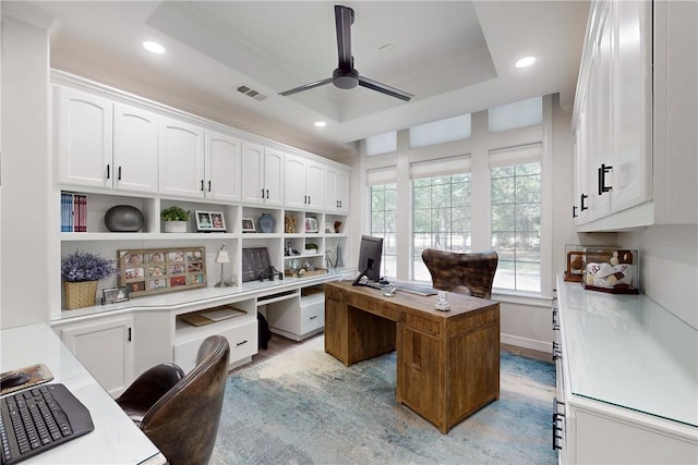 office with a tray ceiling and ceiling fan