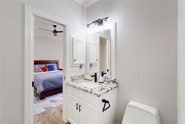 bathroom featuring vanity, crown molding, hardwood / wood-style flooring, ceiling fan, and toilet