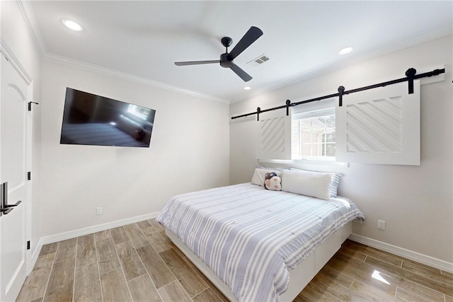 bedroom featuring a barn door, ceiling fan, and crown molding