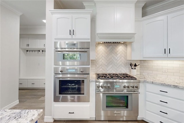 kitchen with tasteful backsplash, white cabinets, and stainless steel appliances