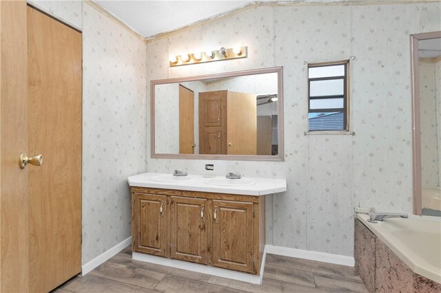 4794 Tall Pine Rd, Navasota, TX 77868 - full bathroom with double vanity, wood finished floors, a garden tub, and wallpapered walls