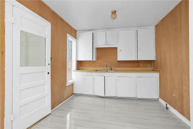 4794 Tall Pine Rd, Navasota, TX 77868 - kitchen with light countertops, white cabinets, light wood finished floors, and wood walls