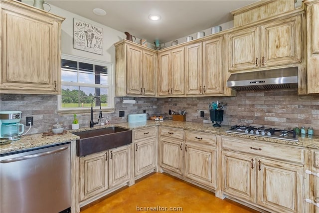 kitchen with appliances with stainless steel finishes, backsplash, light brown cabinetry, light stone counters, and sink