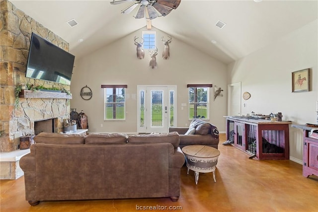 living room with ceiling fan, a stone fireplace, and high vaulted ceiling