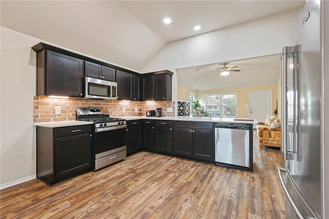 kitchen with backsplash, vaulted ceiling, light wood-type flooring, light countertops, and stainless steel appliances