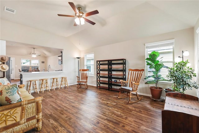 living area with a healthy amount of sunlight, a ceiling fan, vaulted ceiling, and wood finished floors