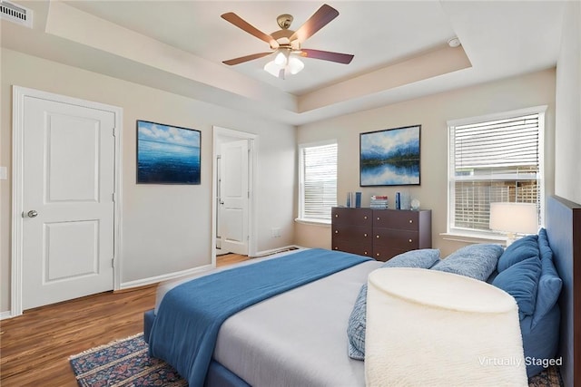1208 High St, Navasota, TX 77868 - bedroom with a raised ceiling, multiple windows, visible vents, and wood finished floors
