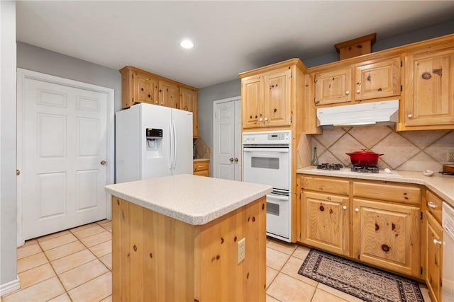 kitchen featuring light tile patterned flooring, a center island, under cabinet range hood, and white appliances