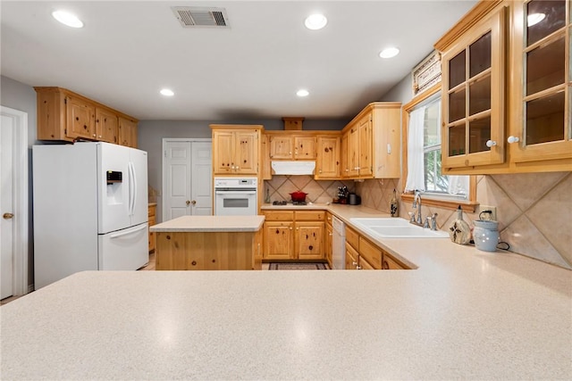 kitchen with a sink, visible vents, white appliances, light countertops, and under cabinet range hood