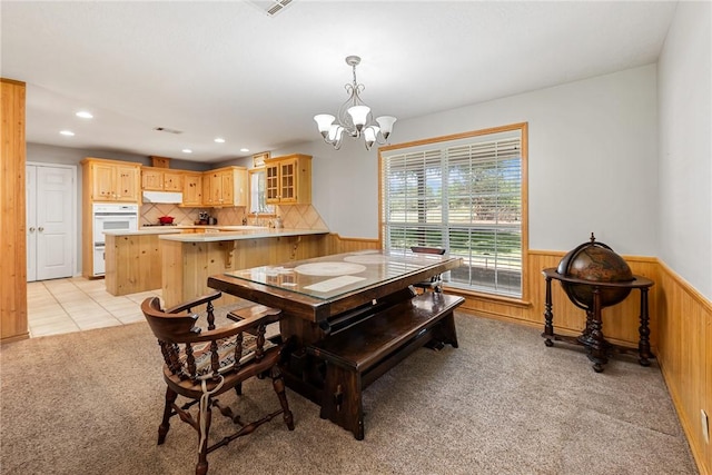 dining area featuring recessed lighting, wood walls, light carpet, wainscoting, and a notable chandelier