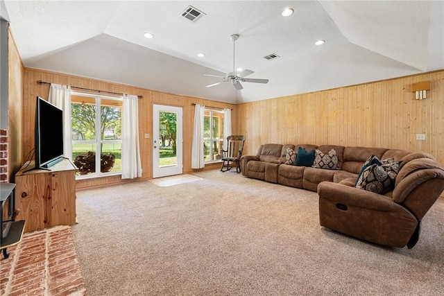 living area with wooden walls, vaulted ceiling, and visible vents