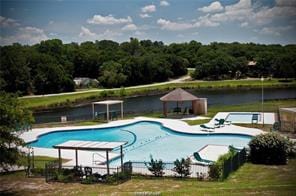 community pool with a view of trees, a water view, and a patio area