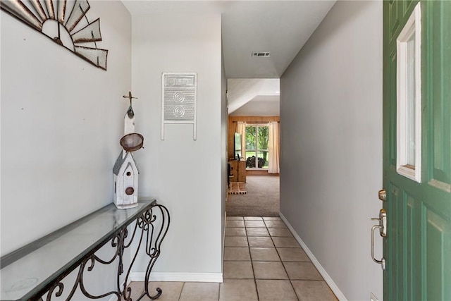 foyer entrance featuring visible vents, baseboards, light tile patterned floors, and light colored carpet