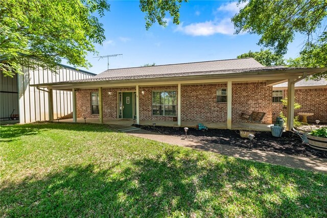 back of house with brick siding and a lawn