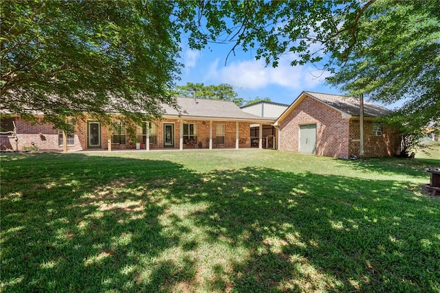 back of property featuring brick siding and a yard